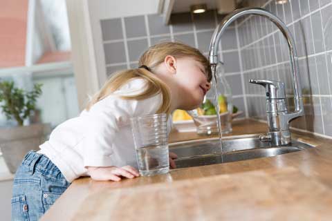 Young Girl Drinking from a Faucet